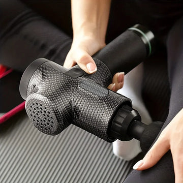 Close-up of a hand holding a black electric percussion massage gun for deep tissue muscle relief.